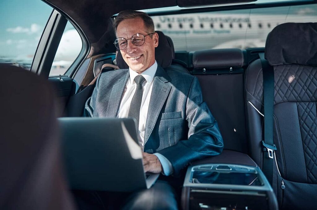 Businessman Using Laptop in Luxury Car