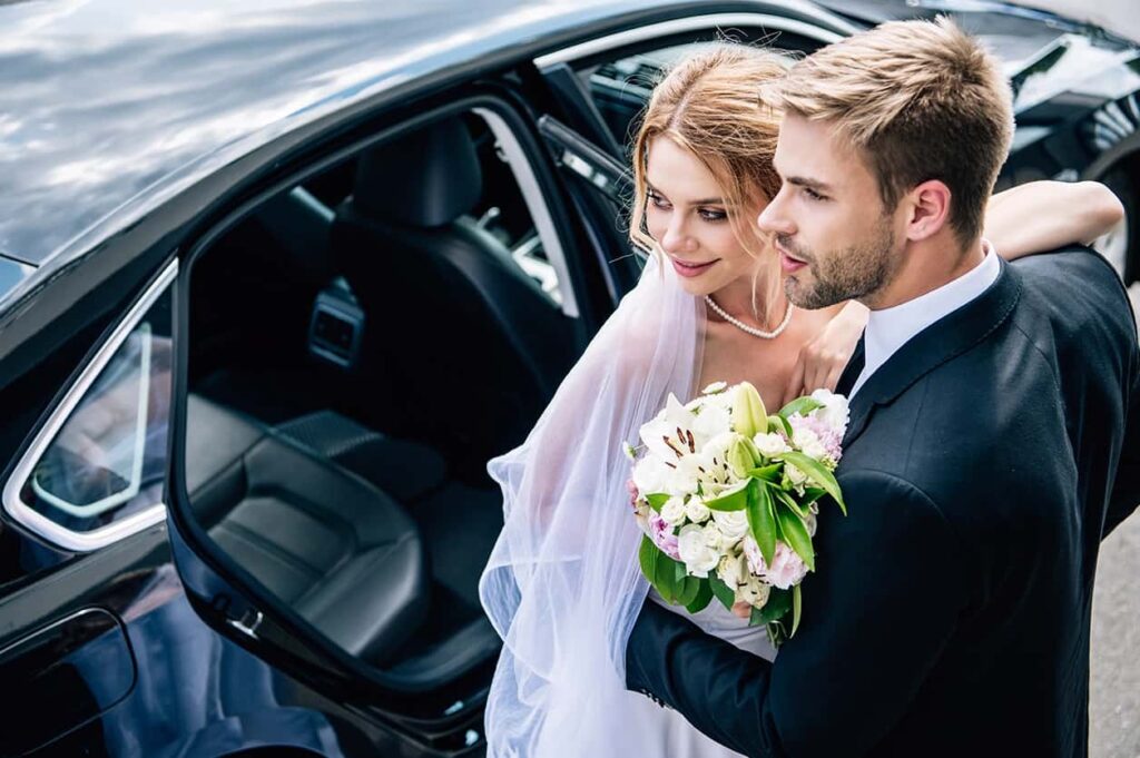 Bride and Groom Next to Wedding Car