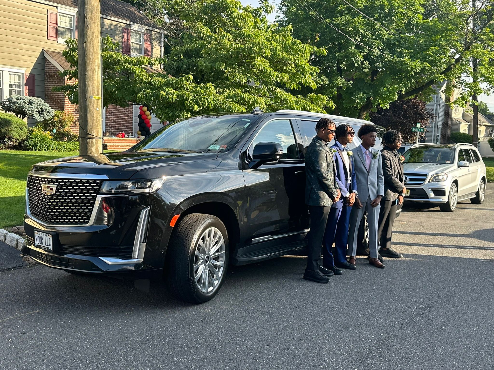 Group of friends posing next to a Cadillac Escalade, ready for their prom night with luxury limo service from Noor Limousine LLC.