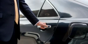 Chauffeur offering luxury limo service from Newark Airport to Manhattan, opening the door for a client.