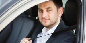 Chauffeur fastening his seatbelt, ready to offer professional limo service in New Jersey.
