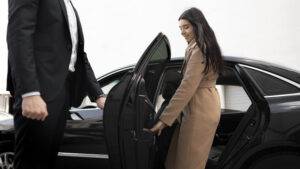 Businesswoman stepping out of a luxury car at Newark Airport, symbolizing reliable airport transfer services to Manhattan.