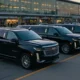 Black luxury SUVs parked outside LaGuardia Airport terminal during evening, showing reliable airport transfer service in NYC.