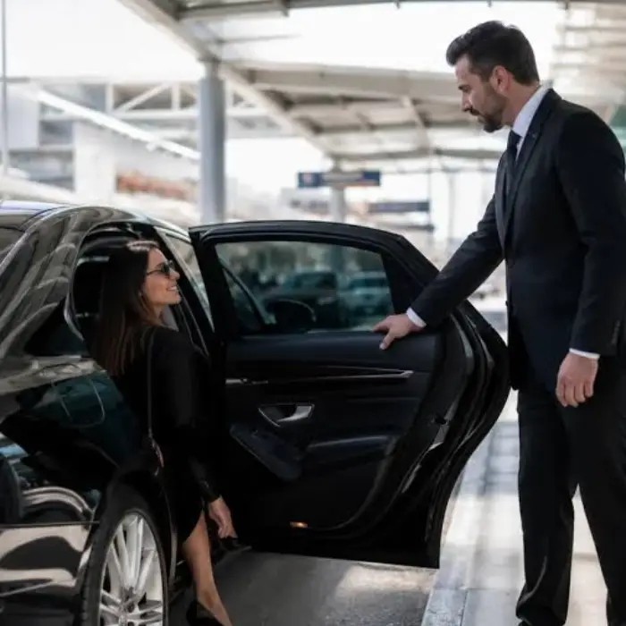 Professional chauffeur assisting passenger with luxury black car and limo service in Howell NJ